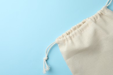 Photo of Cotton eco bag on light blue background, top view. Space for text