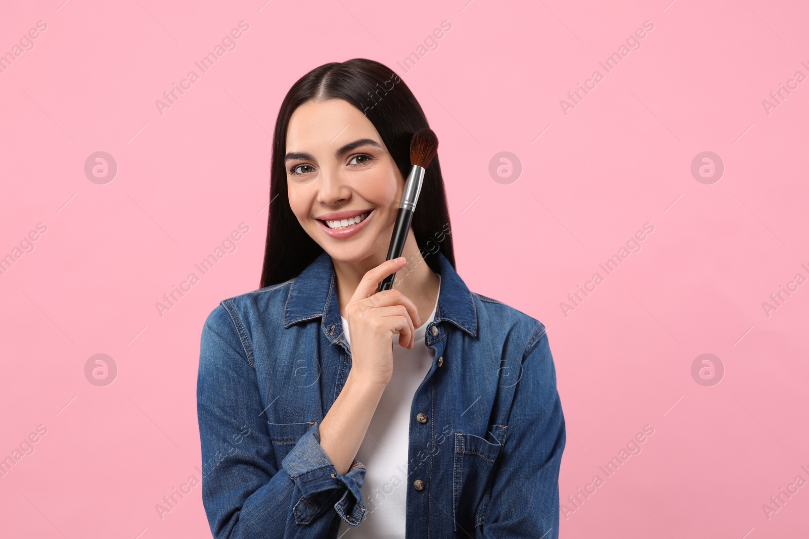 Photo of Beautiful woman with makeup brush on pink background