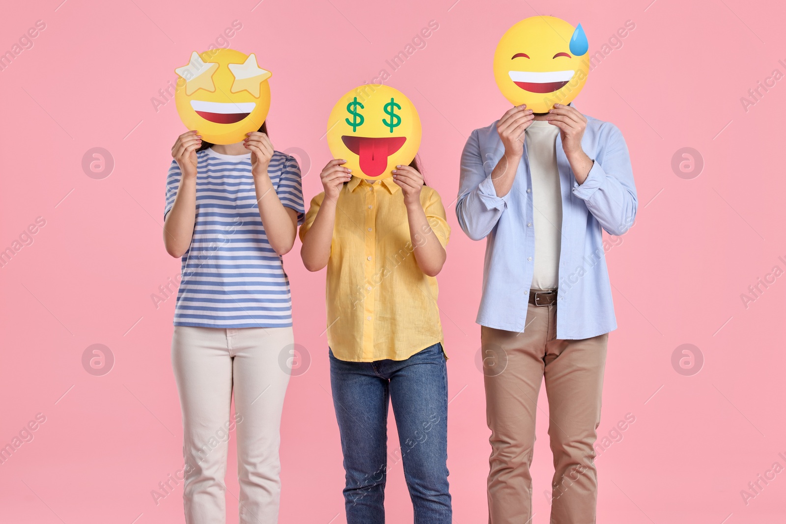 Photo of People covering faces with emoticons on pink background