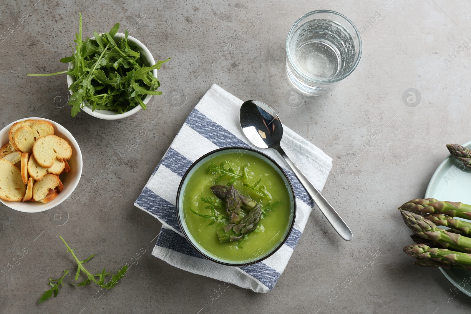 Photo of Delicious asparagus soup served on grey table, flat lay