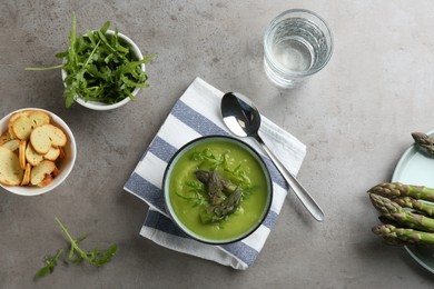 Photo of Delicious asparagus soup served on grey table, flat lay