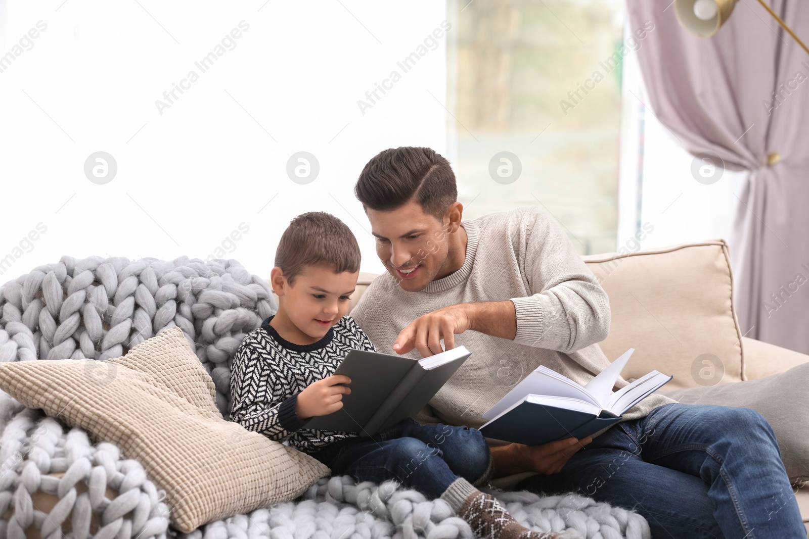 Photo of Father and his son reading books at home. Winter vacation