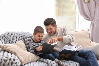 Father and his son reading books at home. Winter vacation