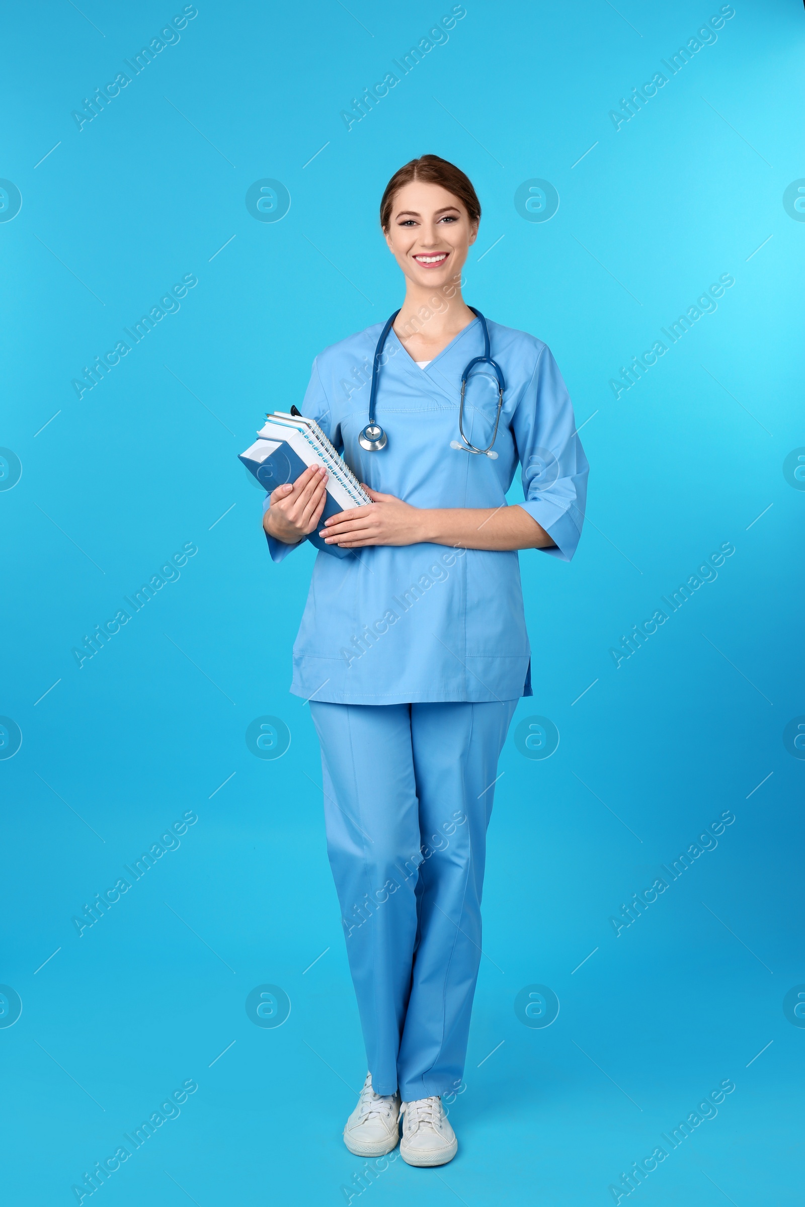 Photo of Young medical student with books on color background