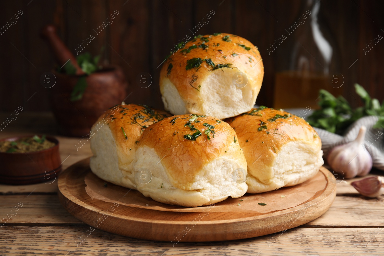 Photo of Traditional pampushka buns with garlic and herbs on wooden table