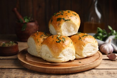 Photo of Traditional pampushka buns with garlic and herbs on wooden table