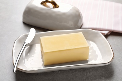 Dish with fresh butter and knife on table