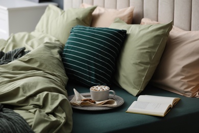 Photo of Cup of drink, cookies and book on bed with new pistachio linens