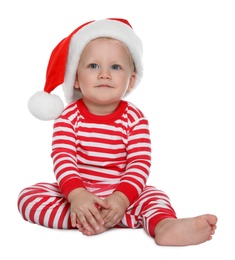 Cute baby in Santa hat and Christmas pajamas sitting on white background