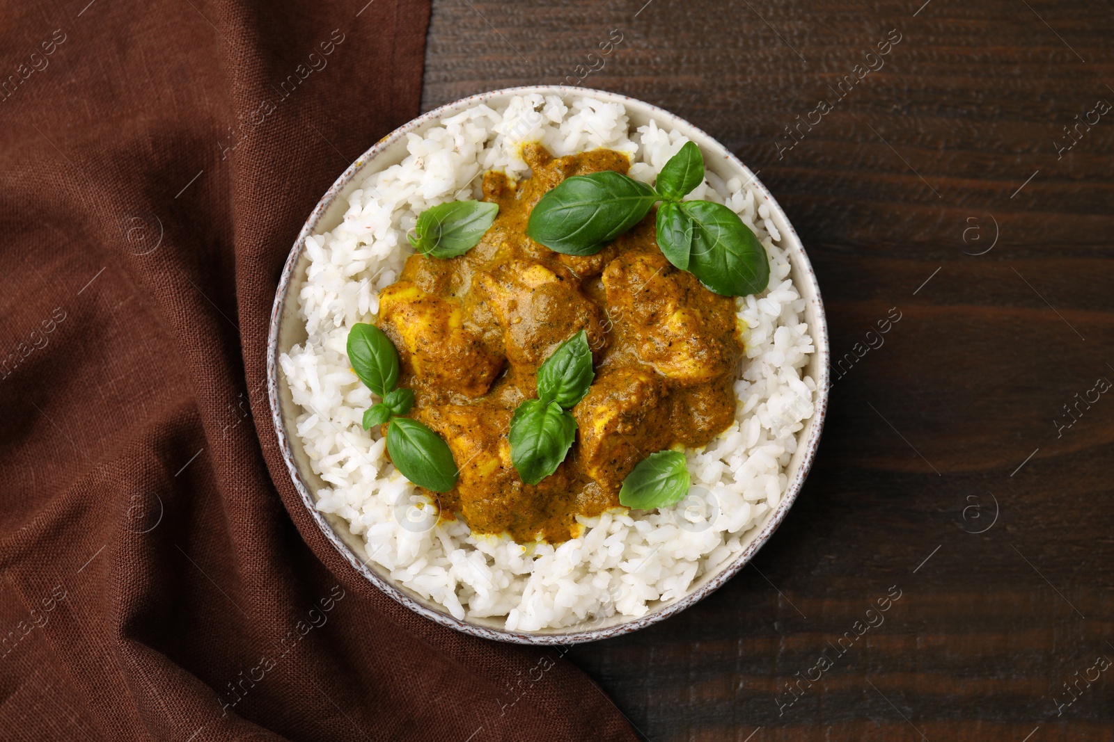 Photo of Delicious rice and chicken with curry sauce served on wooden table, top view