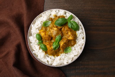 Delicious rice and chicken with curry sauce served on wooden table, top view