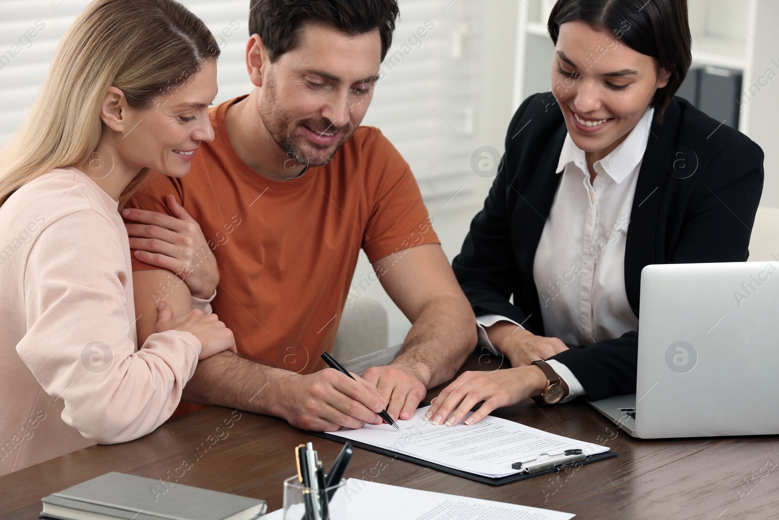 Photo of Professional notary helping couple with paperwork in office