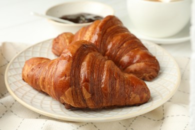 Plate with tasty croissants on white table, closeup