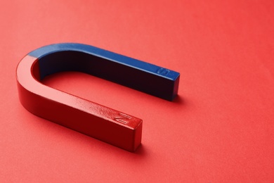 Photo of Red and blue horseshoe magnet on color background. Space for text