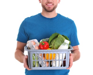 Photo of Delivery man holding plastic crate with food products on white background, closeup