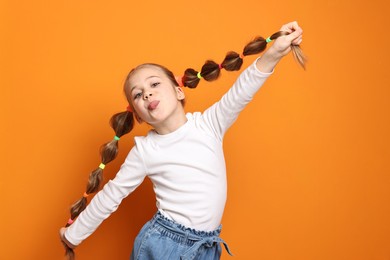 Cute little girl with beautiful hairstyle having fun on orange background