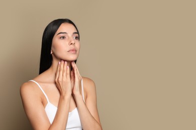 Photo of Young woman doing thyroid self examination on beige background. Space for text