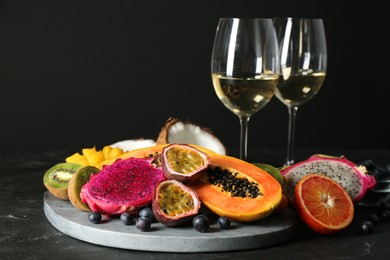 Delicious exotic fruits and wine on black table