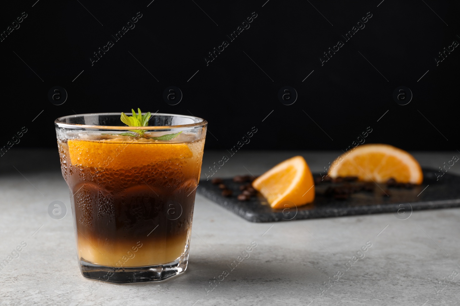 Photo of Tasty refreshing drink with coffee and orange juice on grey table, space for text