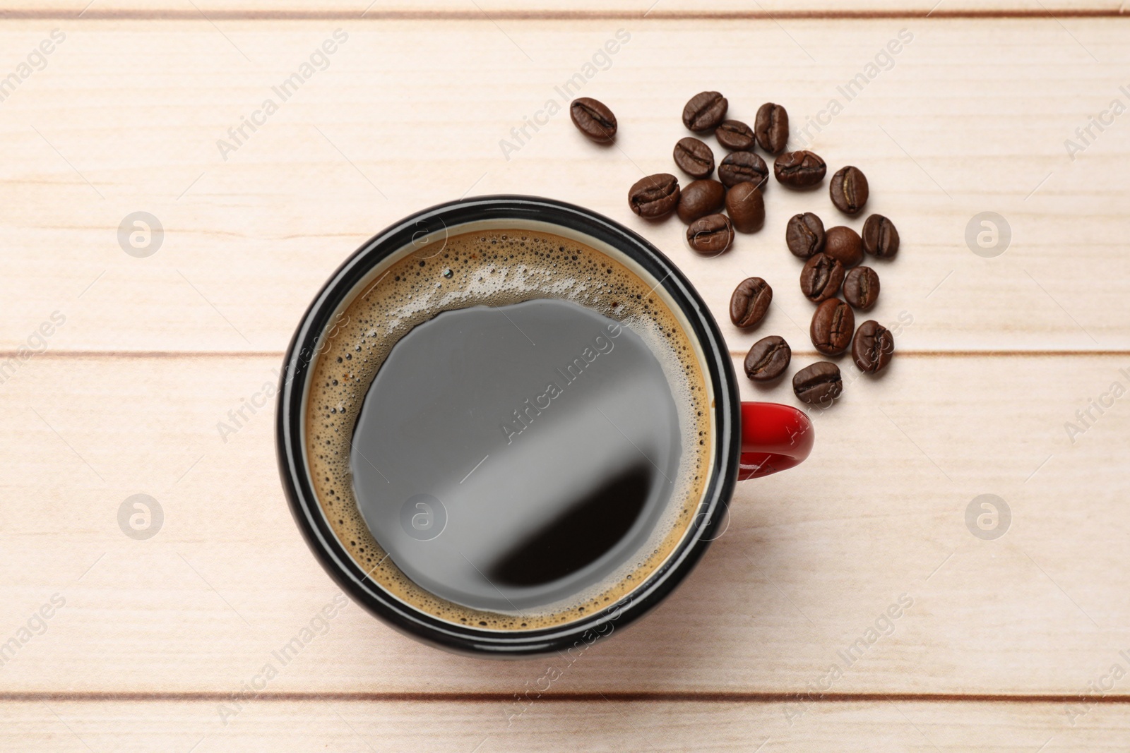 Photo of Cup of aromatic coffee and beans on light wooden table, top view