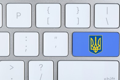 Image of Blue button with Ukrainian coat of arms on keyboard, top view