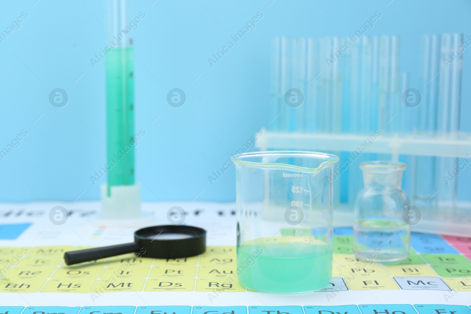 Photo of Beaker and magnifying glass on periodic table of chemical elements