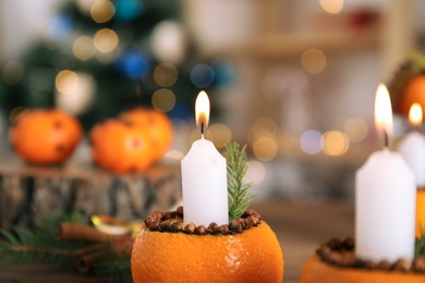 Burning candle in tangerine peel as holder against blurred background, closeup