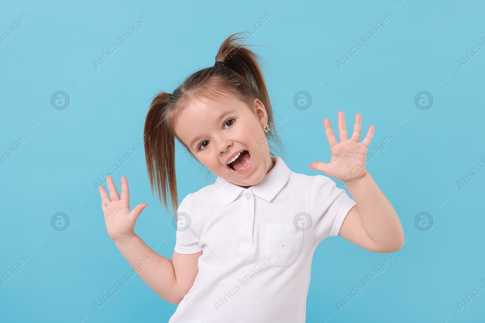 Photo of Portrait of emotional little girl on light blue background