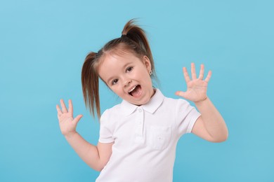 Portrait of emotional little girl on light blue background