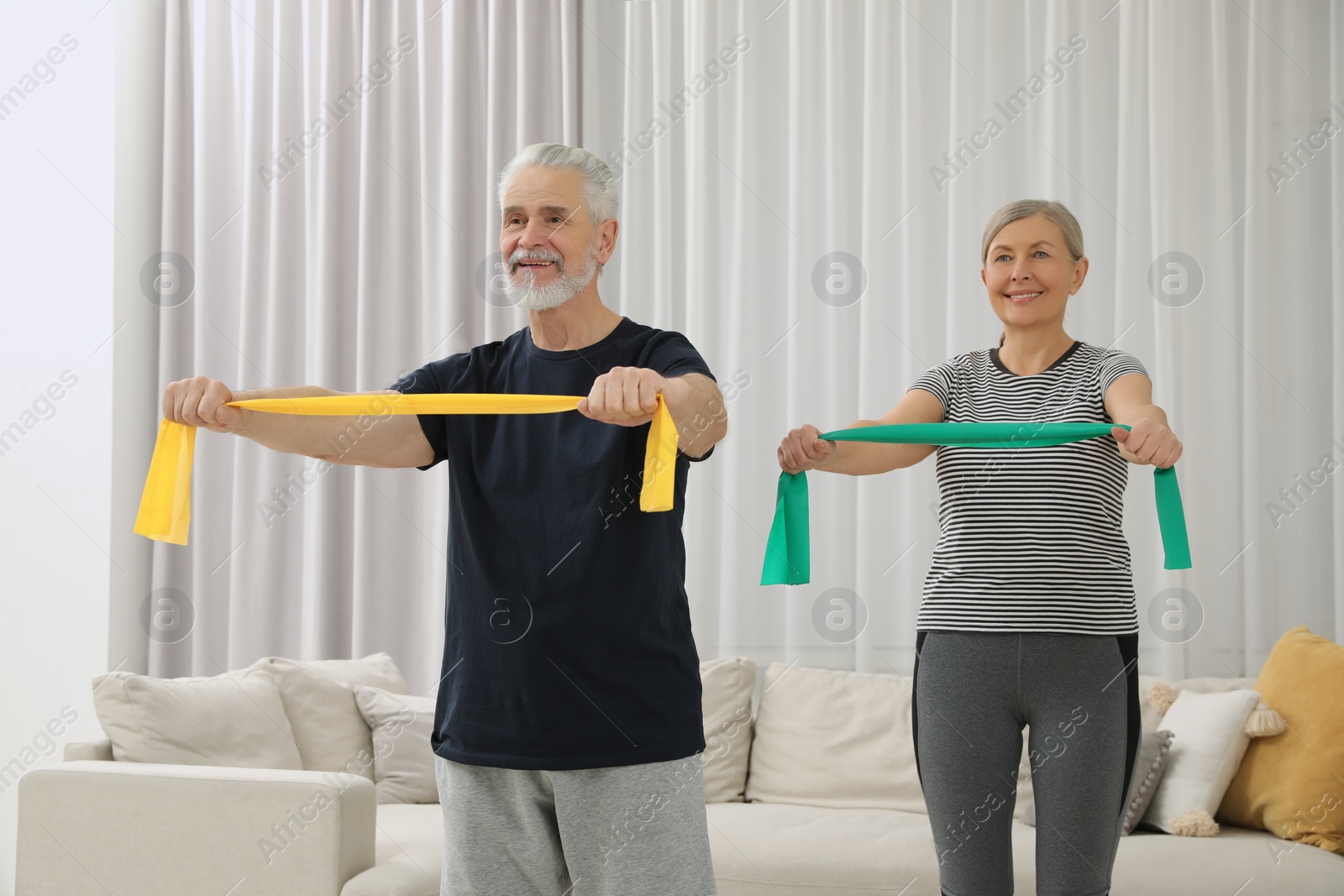 Photo of Senior couple doing exercise with fitness elastic bands at home