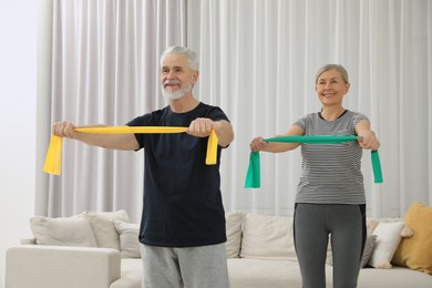 Photo of Senior couple doing exercise with fitness elastic bands at home