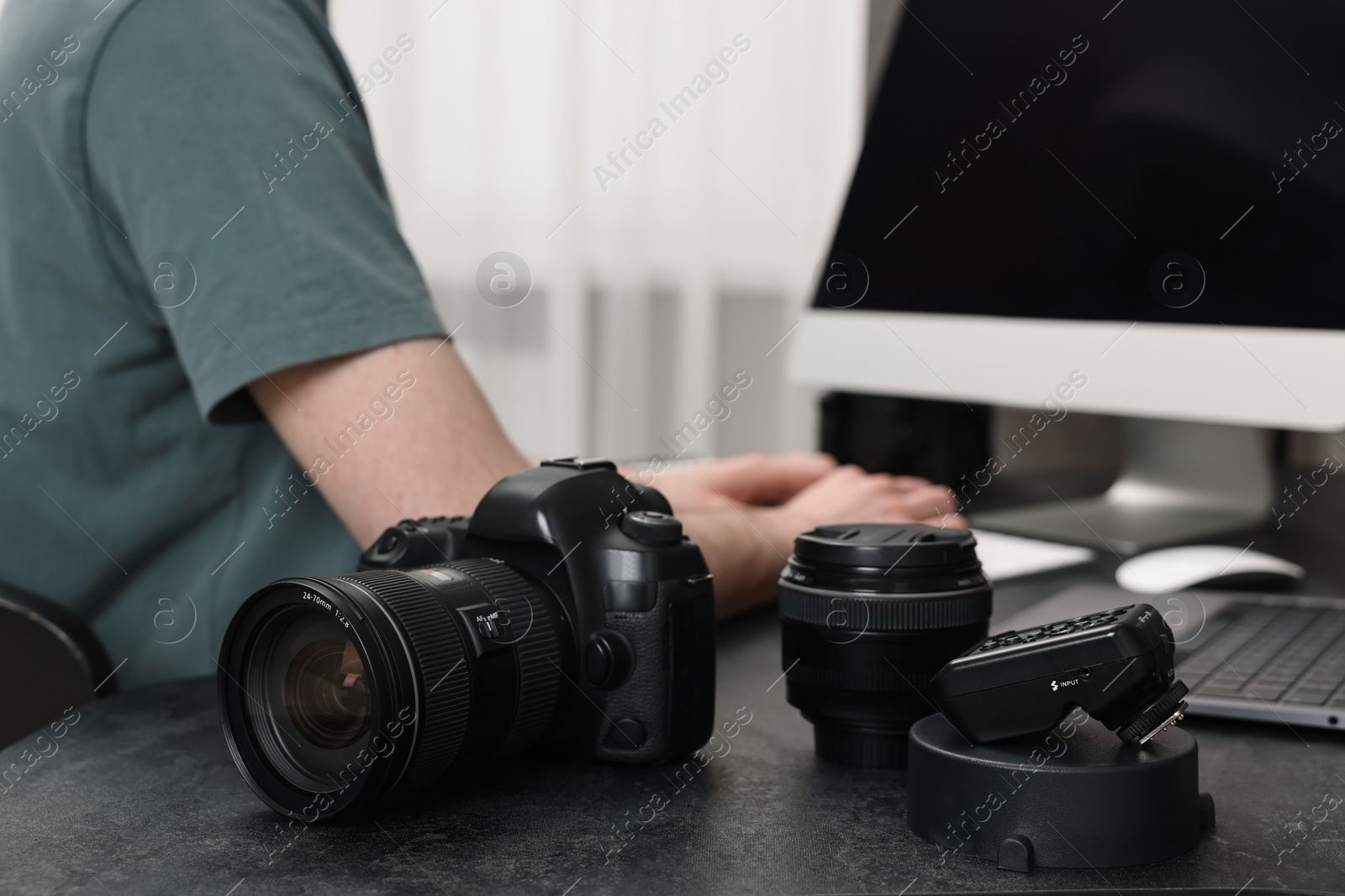 Photo of Camera on dark table, closeup. Photographer working with computer indoors, selective focus