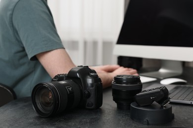 Camera on dark table, closeup. Photographer working with computer indoors, selective focus