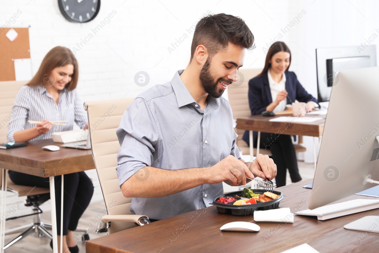 Photo of Office employees having lunch at workplace. Food delivery