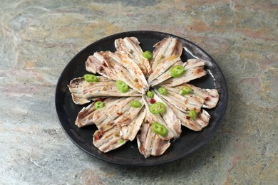 Photo of Tasty pickled anchovies with spices on textured table