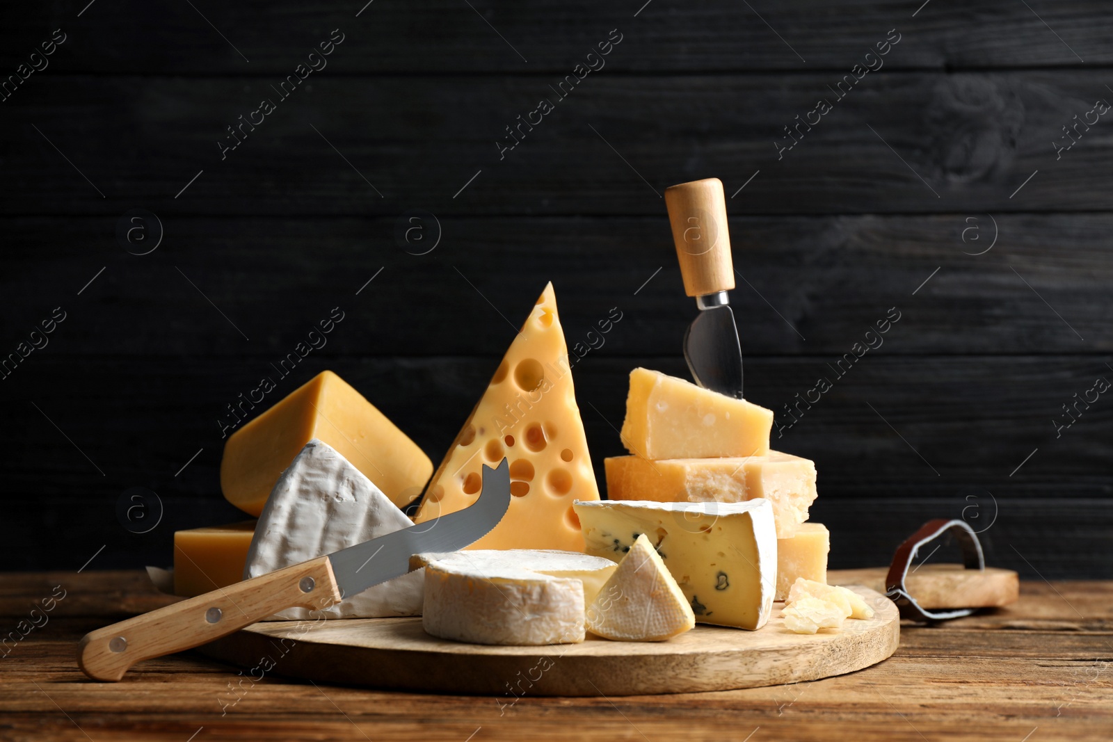 Photo of Different sorts of cheese and knives on wooden table