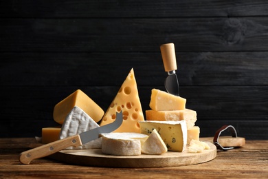 Photo of Different sorts of cheese and knives on wooden table