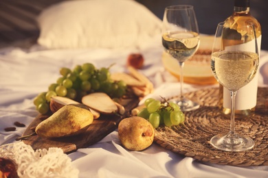 Photo of Delicious food and wine on white picnic blanket