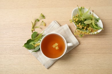 Cup of tea with linden blossom on wooden table, flat lay