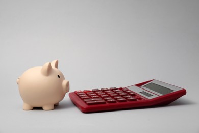 Photo of Calculator and piggy bank on grey background