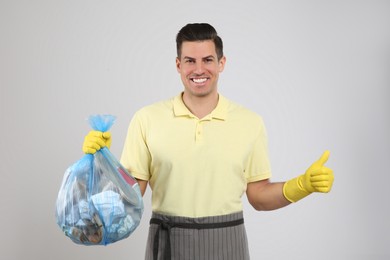 Photo of Man holding full garbage bag on light background