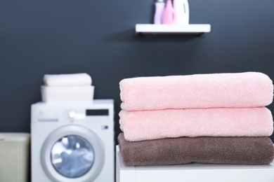 Photo of Stack of clean towels on table in laundry room. Space for text