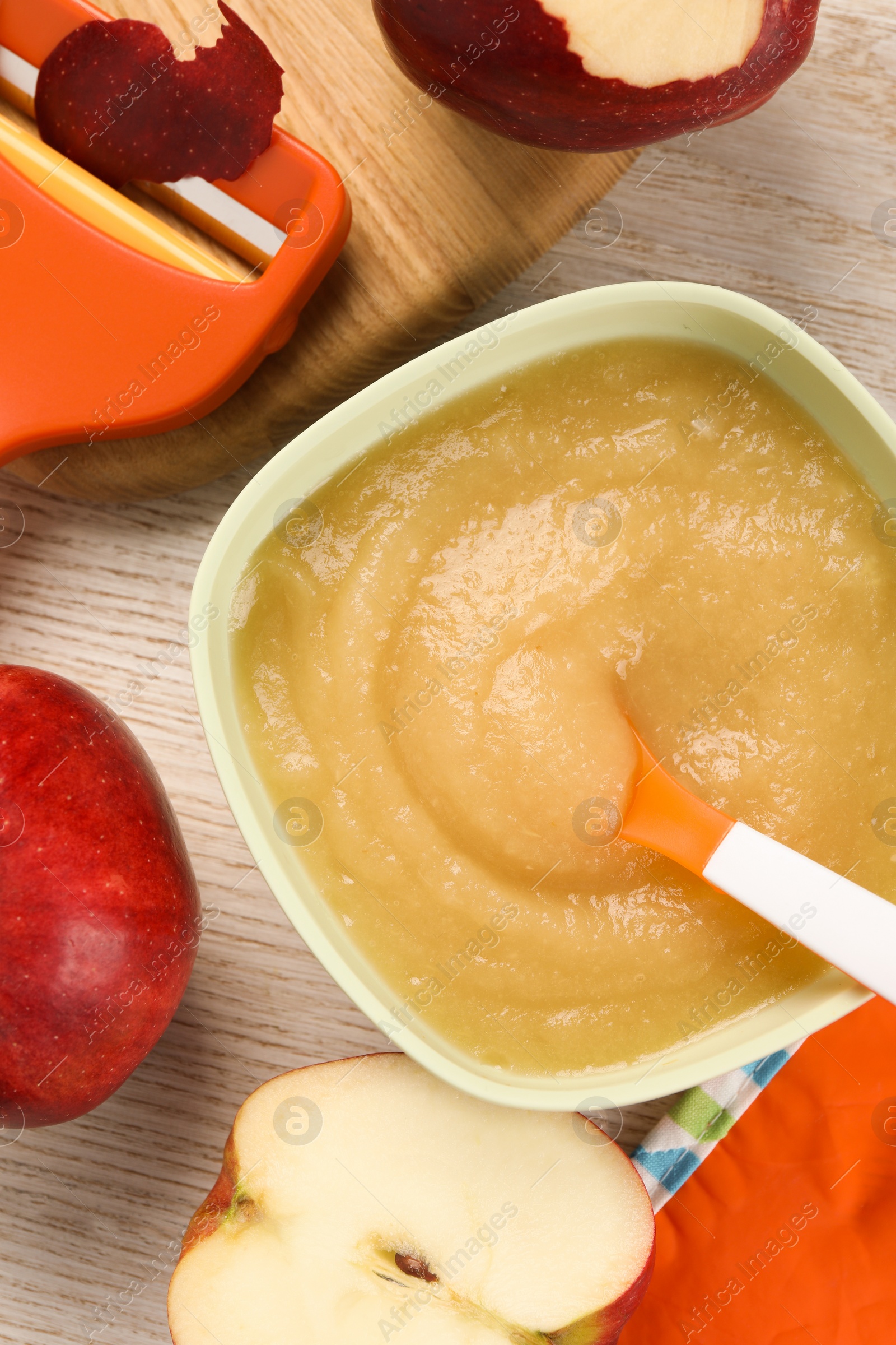 Photo of Healthy baby food. Bowl with delicious apple puree and fresh fruits on white wooden table, flat lay