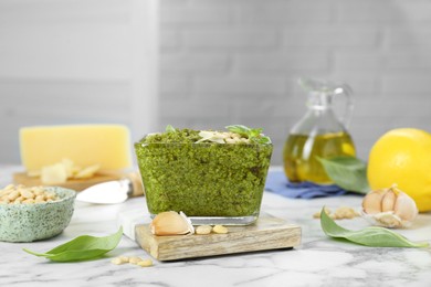 Delicious pesto sauce and ingredients on white marble table