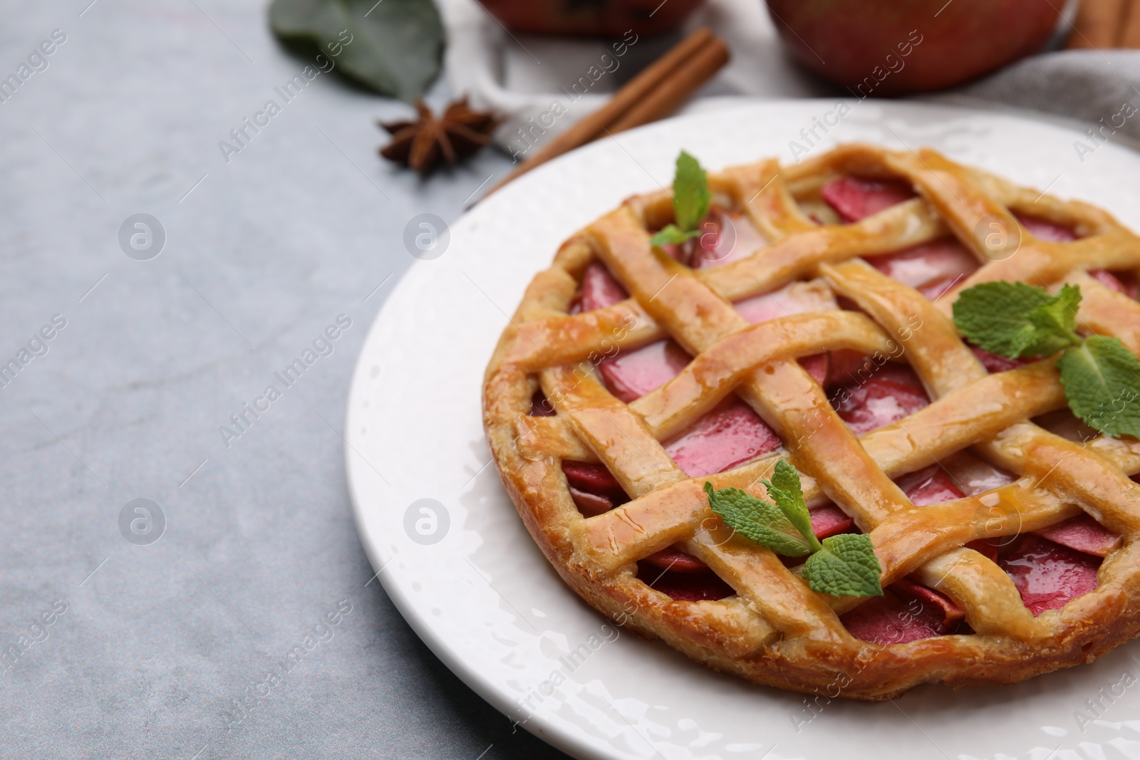 Photo of Delicious apple pie with mint on grey table, closeup. Space for text