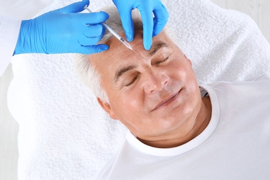 Senior man getting facial injection in clinic. Cosmetic surgery concept