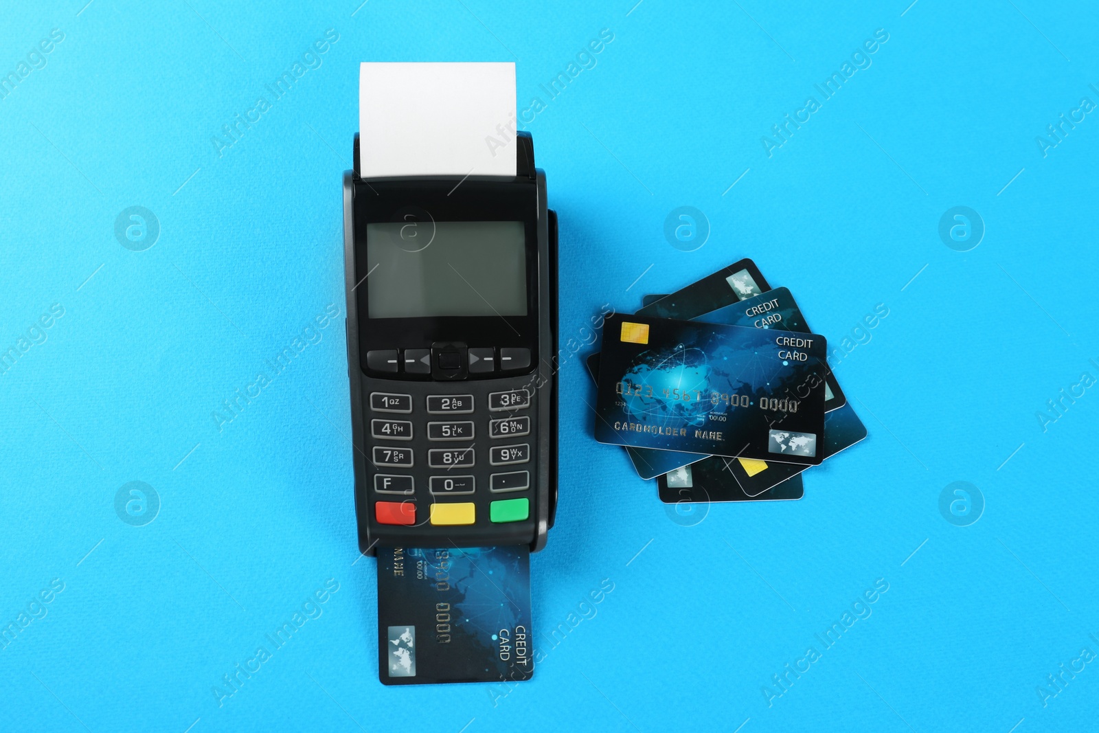 Photo of New modern payment terminal and credit cards on light blue background, flat lay