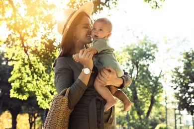 Young mother with her cute baby in park on sunny day