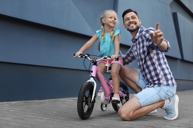 Father teaching daughter to ride bicycle on street