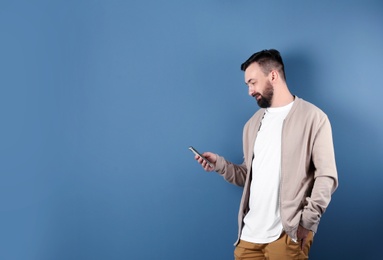 Photo of Portrait of handsome bearded man with mobile phone on color background